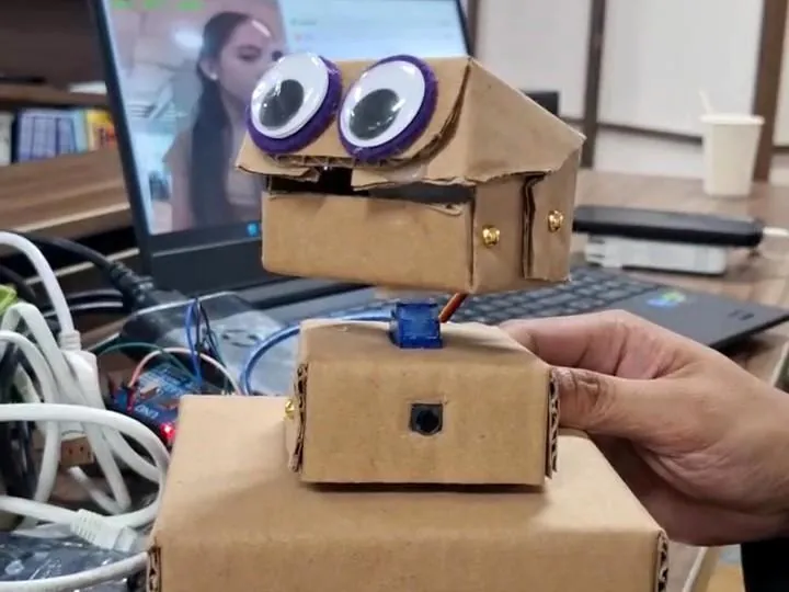 Fitting servos by hand into the cardboard prototype in front of a laptop
