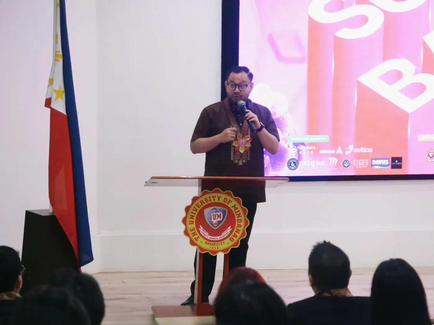 Raphael Rey Bacolod delivering the keynote at the University of Mindanao podium