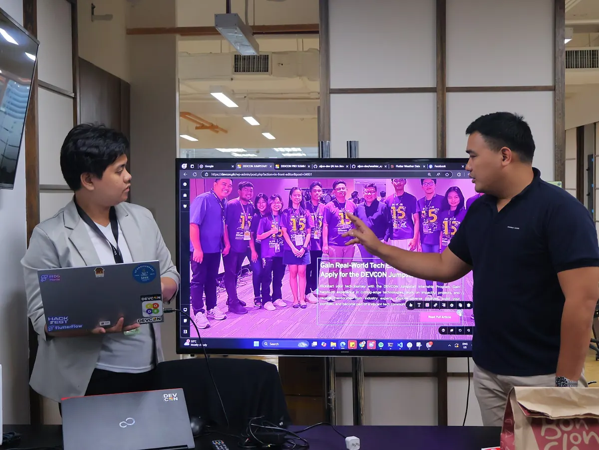 An intern and a mentor discussing the Jumpstart internship page on a large screen